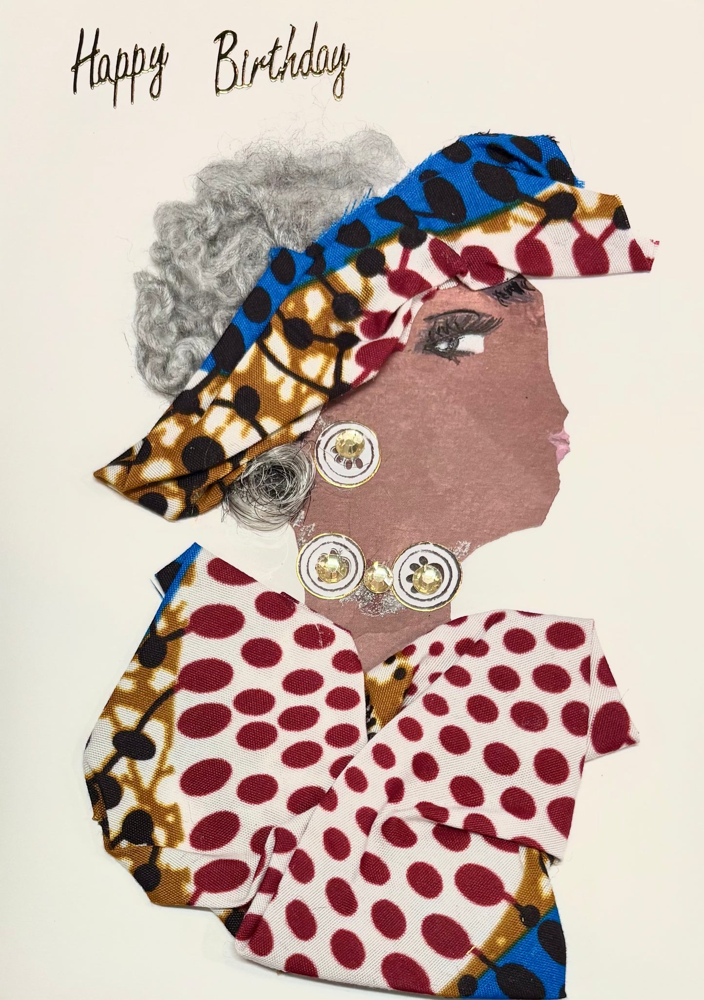 A woman with grey hair has a matching headband and blouse with red, white, blue, and yellow. The pattern has lots of dots. Her earrings and necklace match as they are made up of white circles. Happy Birthday is written in the top left corner in gold.