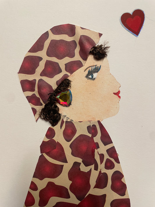 Handmade card of a woman in a full red-and-tan giraffe-print outfit with matching headwrap. She has curly dark hair, large multicolor gem earrings, and a red heart sticker above her head.