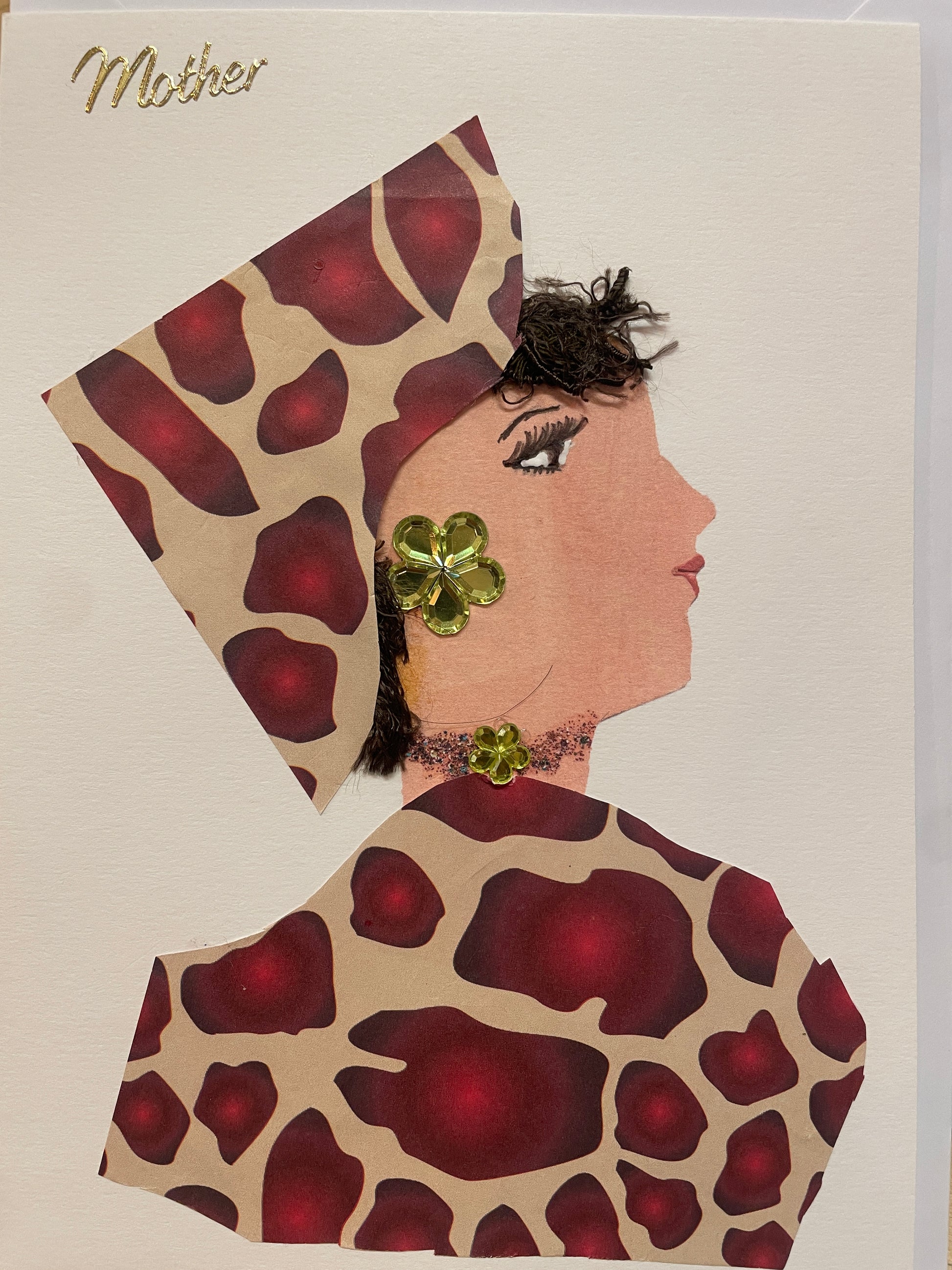This is a handmade card of a woman named Royal Ruby Regent, wearing a red and tan patterned outfit and head wrap, green gem jewellery, and a textured brown hairstyle. The word "Mother" is displayed in gold in cursive in the top left corner