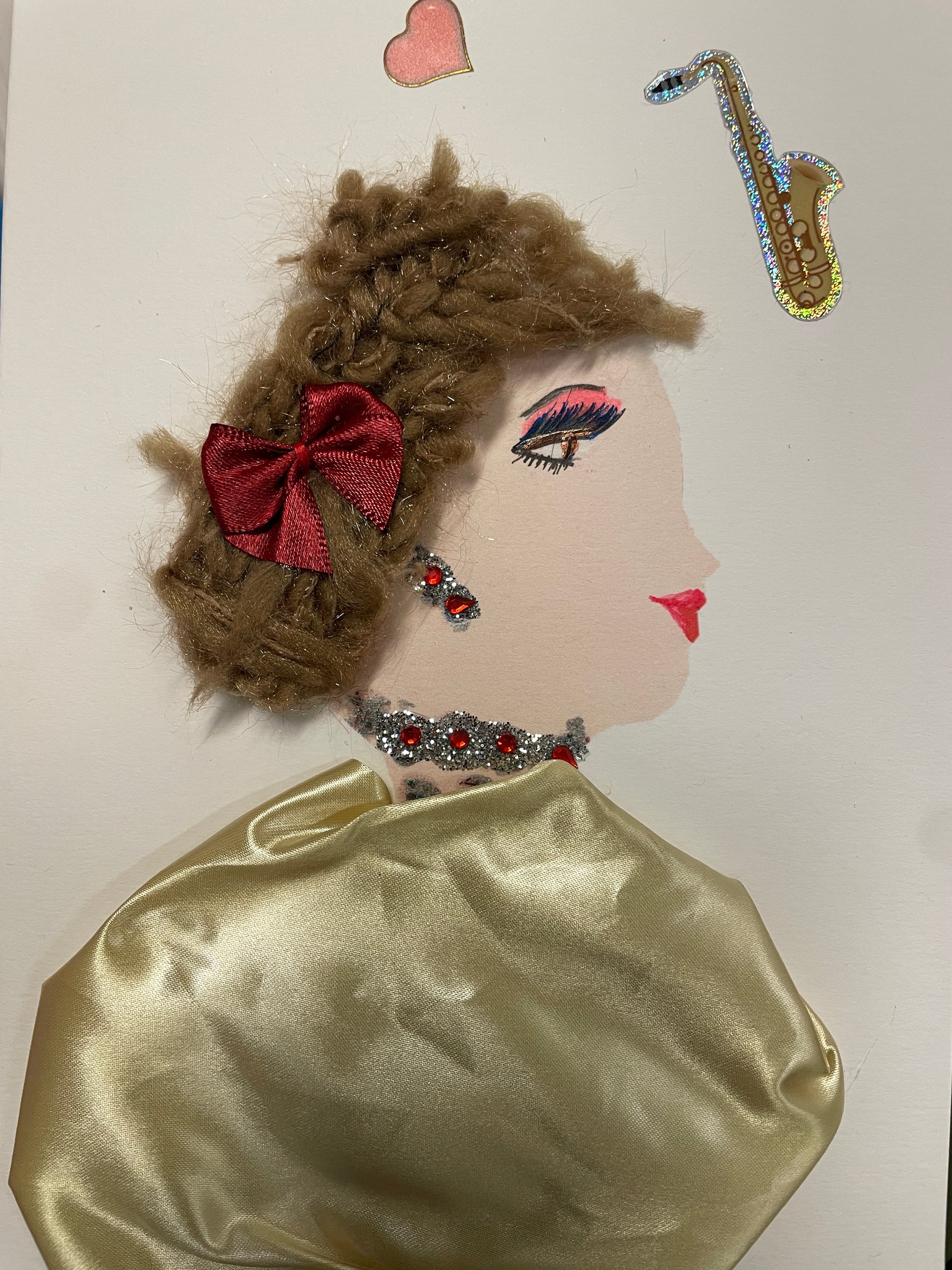 Handmade card of a woman with textured brown braided hair, red bow, jeweled earrings and choker, and a champagne satin gown. A saxophone and pink heart float above her.