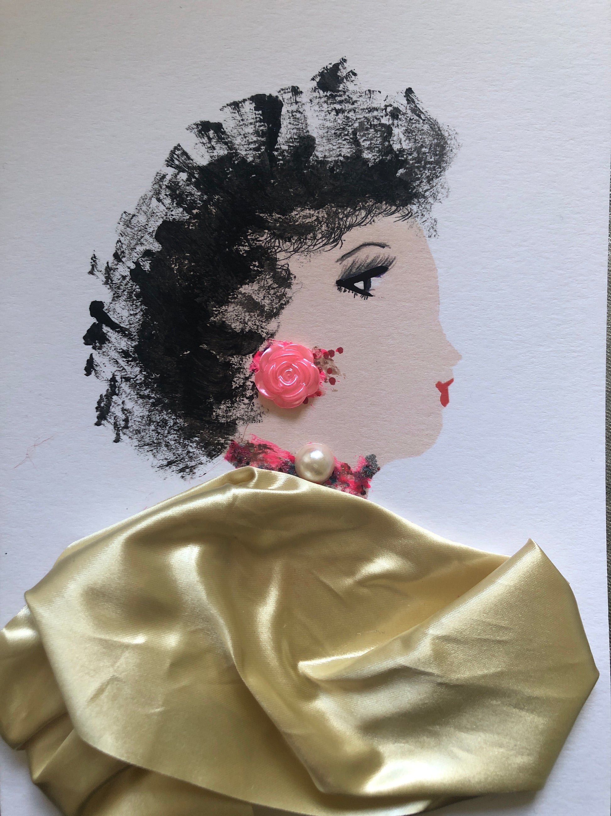 This is a handmade card of a woman named Sweet Potato Chief. Her hair is painted in bold black brushstrokes, giving a soft, natural texture. She wears a shiny gold fabric outfit. A small pink rose sits on her ear like an earring, and a pearl rests at her neck above a pink and black necklace.