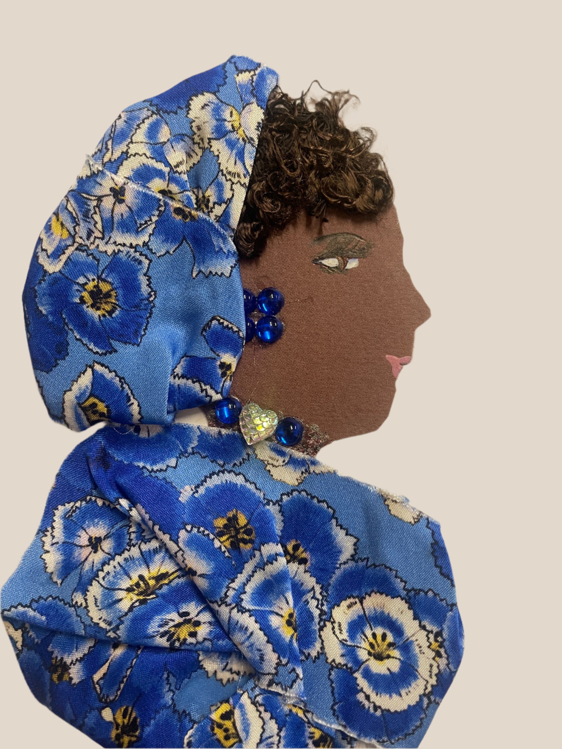 This is a handmade card of a woman named Venus Victoria. She wears a blue floral wrap with a matching head wrap, blue gems, and a sparkling heart gem at her collar.
