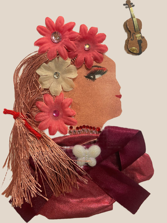 This is a handmade card of a woman named Viola Vauxhall. She wears large pink and cream flower accessories in her hair, a necklace of red gems, and a deep burgundy bow with a pearl butterfly. There’s a violin sticker in the top corner.