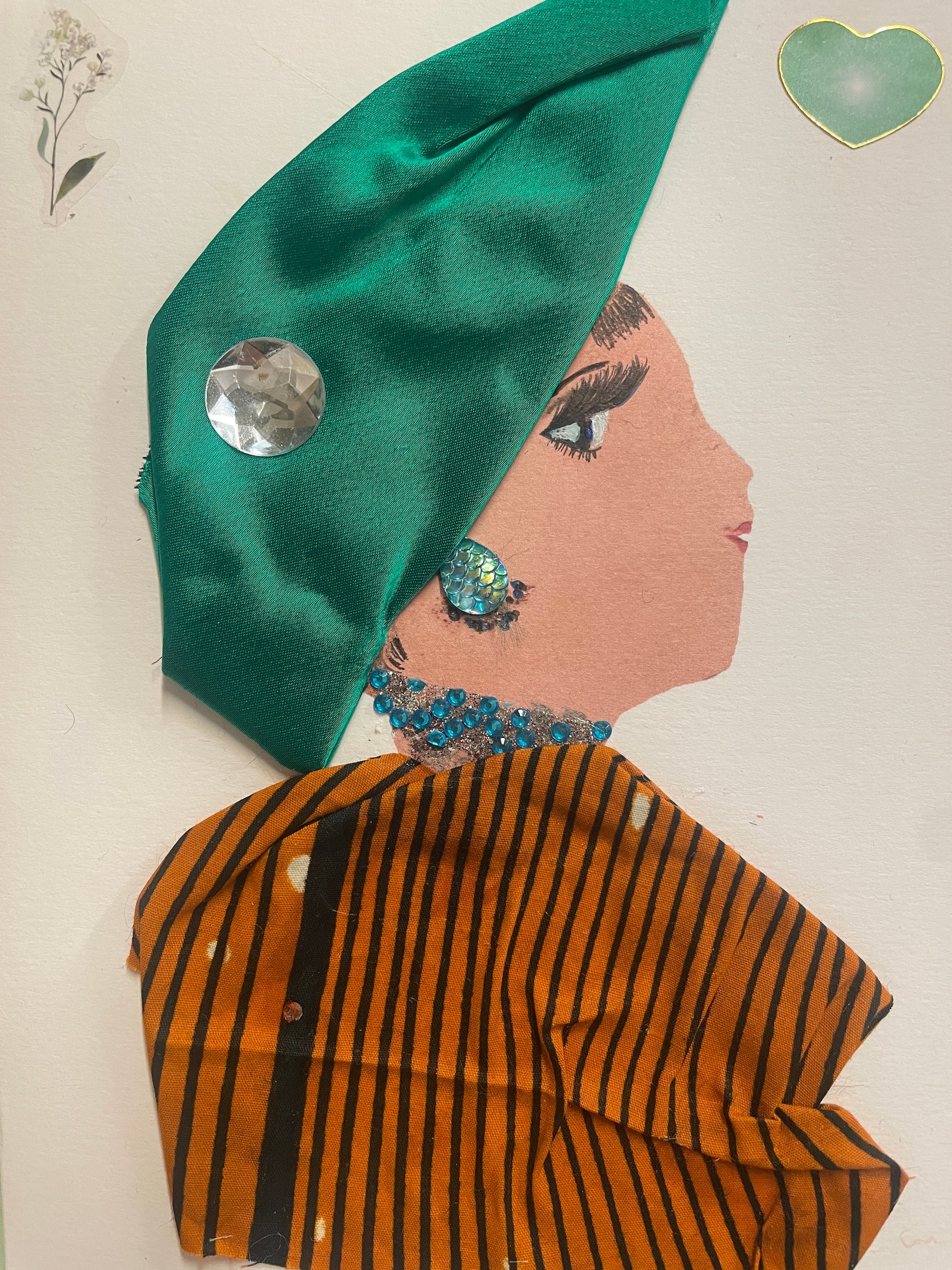 This is a handmade card of a woman named Zayna Zone. She wears a shiny green head wrap, turquoise gem jewellery, and a burnt orange and black striped top. Green and white floral stickers appear in the background.