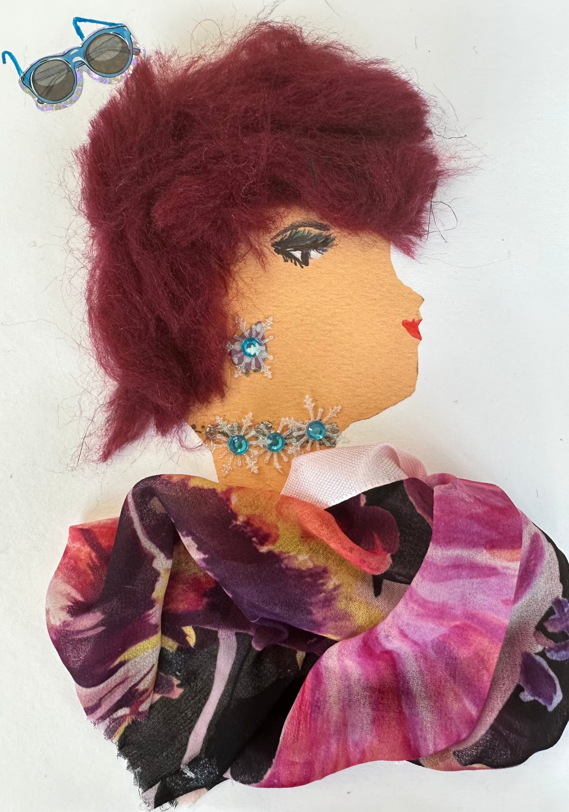 I designed this handmade card of a woman named Gloucester Gail. She is dressed in a pink and purple patterned chiffon blouse. She has a snowflake shaped earring and necklace which match the colour of the blue and white sunglasses.