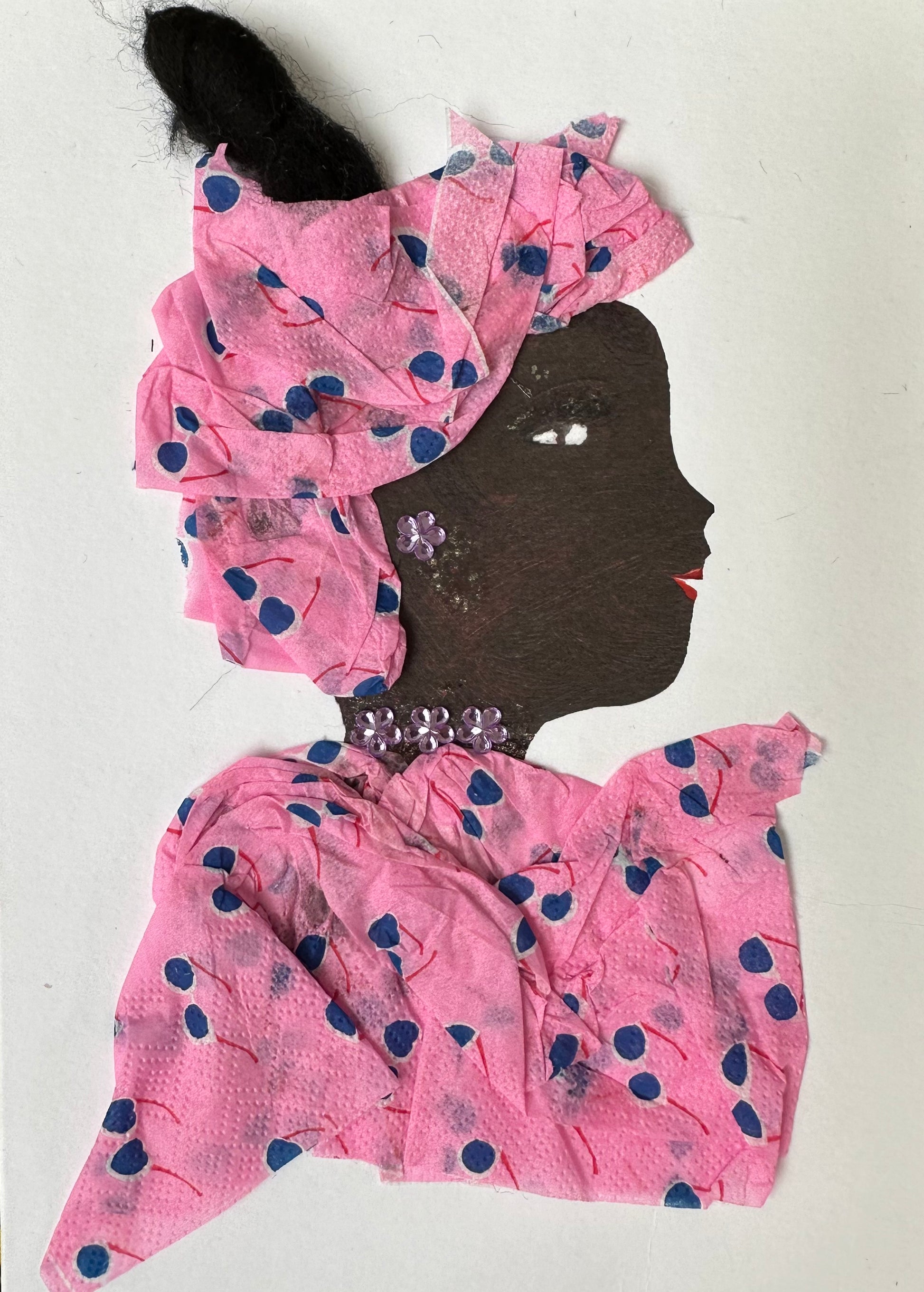 I designed this handmade card of a woman dressed in a matching blouse and hatinator. The material is pink with a blue and white sunglasses pattern. She has light pink flower-shaped, gemstone earrings and necklace.