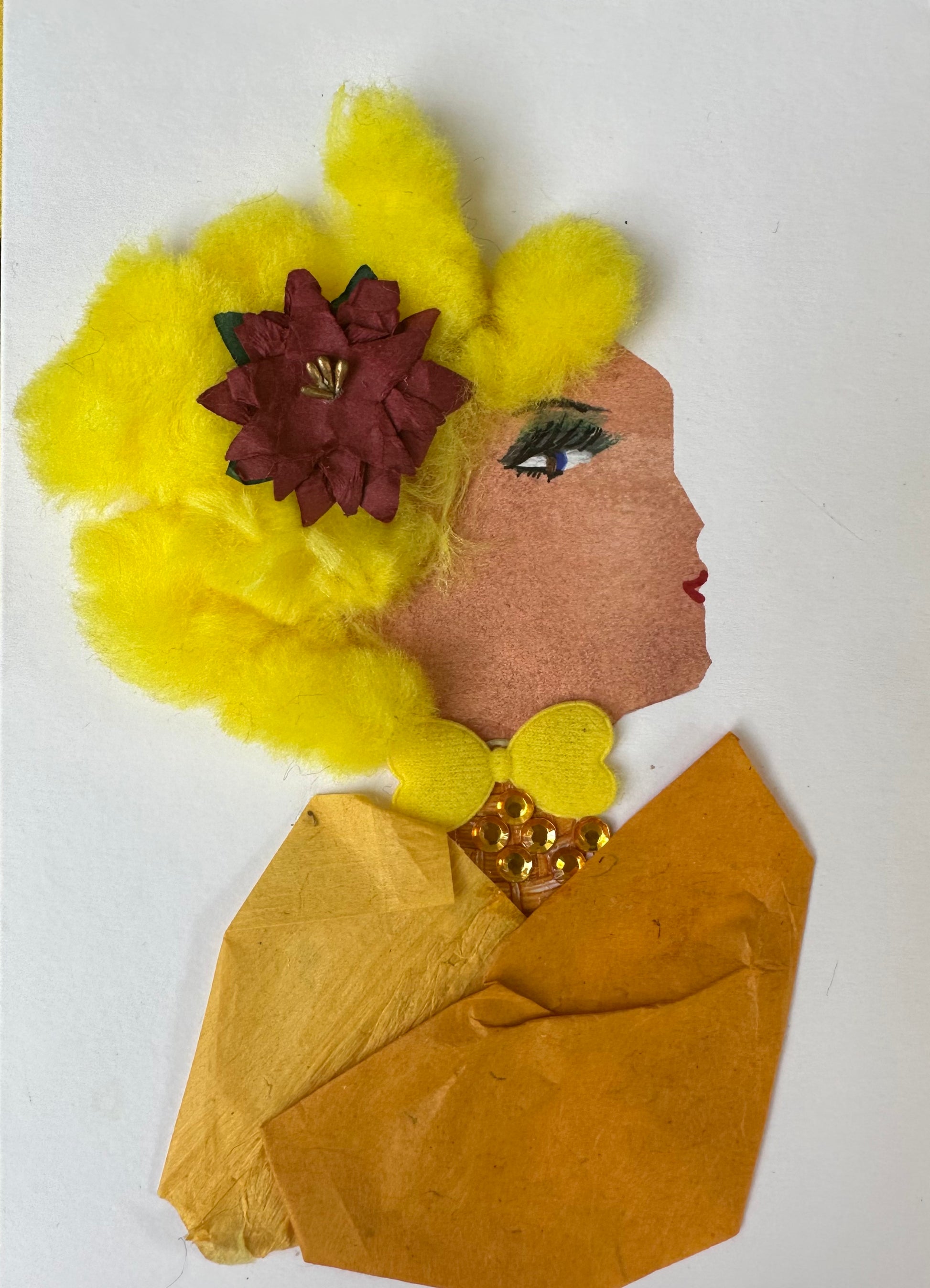 I designed this handmade card of a woman dressed in a honey coloured blouse. Her collar is a bright yellow bow that touches her orange gemstone necklace. Her hair is a bright yellow, with a fluffy texture; it is clipped together with a red poinsettia flower.