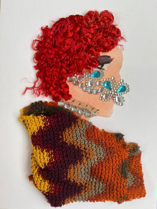 This card is called Georgia Joy. She wears a fun orange patterned blouse and has curly red hair. She wears a crystal mask on her face which is blue.