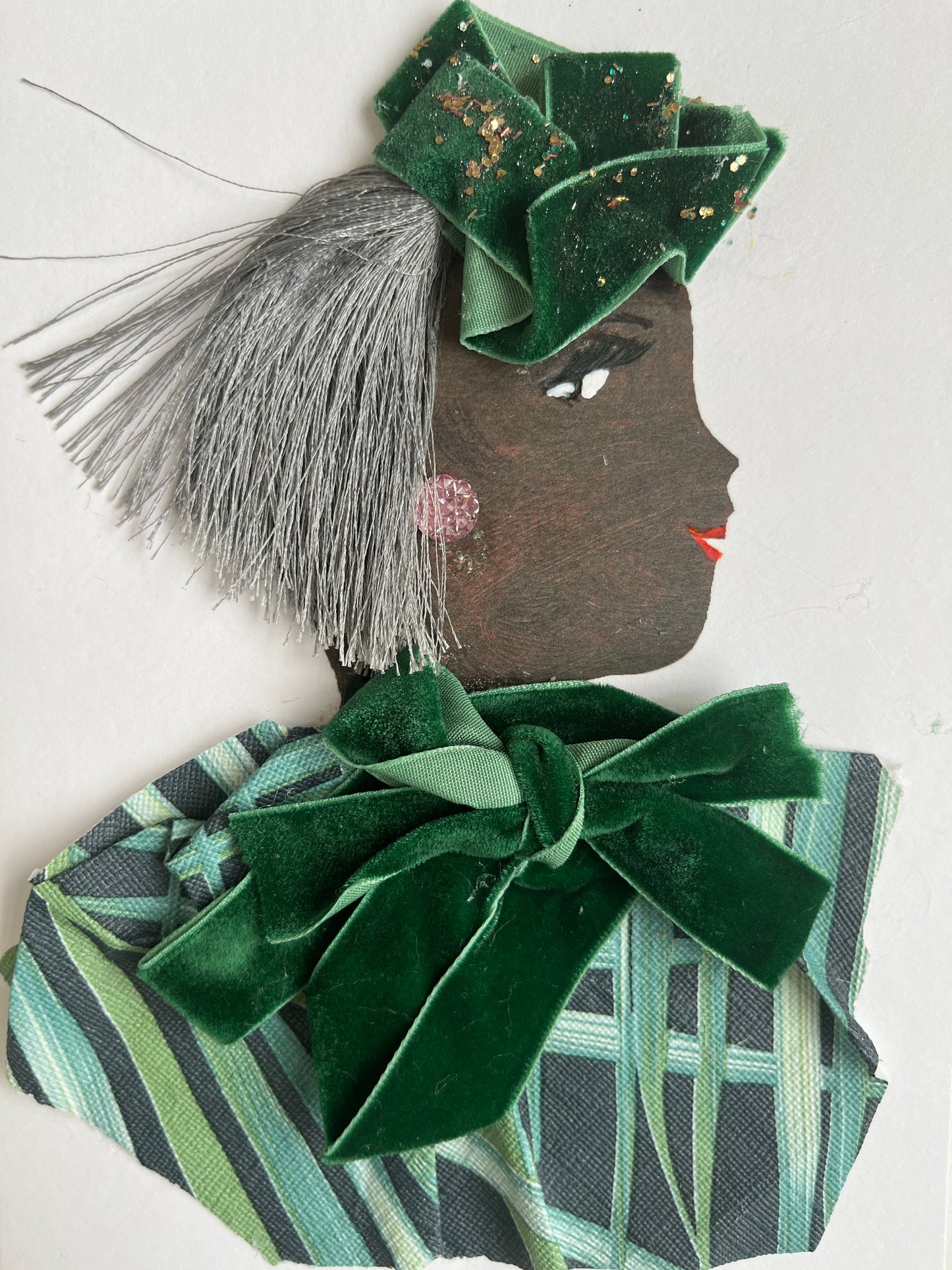 This card is of a woman given the name Piper Potts. Piper wears a blouse that is plant printed with a large green velvet bow around her neck. Her hair is short and silver, and she wears a ribbon hat with gold flakes on her head.