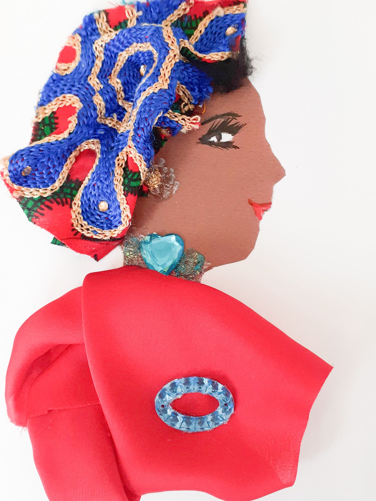 I designed this card of a woman and gave her the name Vancouver Vah Vah Voom. She has a brown skin tone and wears a red silk blouse with a small blue oval gemstone on the front of it. Her necklace is a blue gem in the shape of a heart. Her headpiece is a royal blue pattern outlined in gold with a red background.