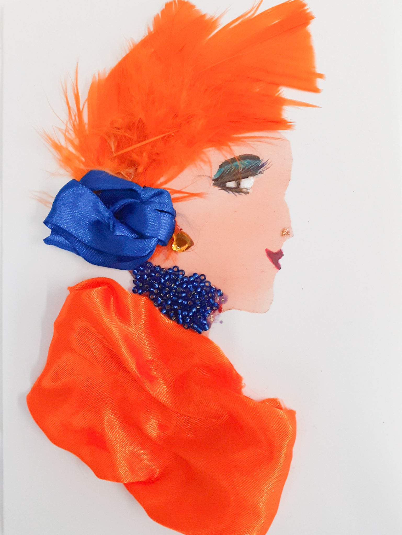 This card is called Citrus Florida. She wears bright orange feathers in her hair with a blue bow, and a blue necklace and orange blouse that matches.
