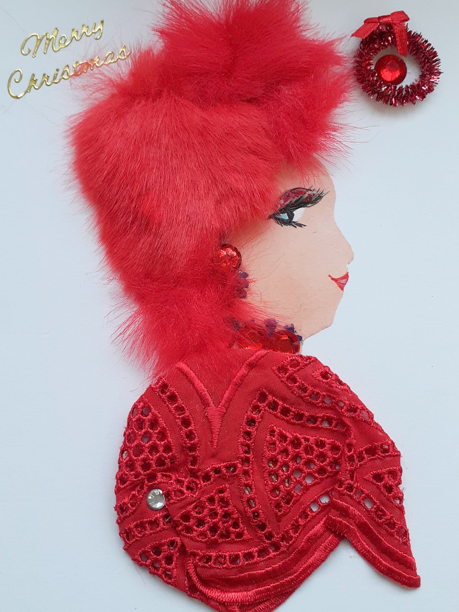 This card has been given the name Dolly. She wears a red eyelet blouse which matches her red furry hair. In the right corner, there is a red wreath. On the left corner, there is a sticker which says "Merry Christmas" in gold.