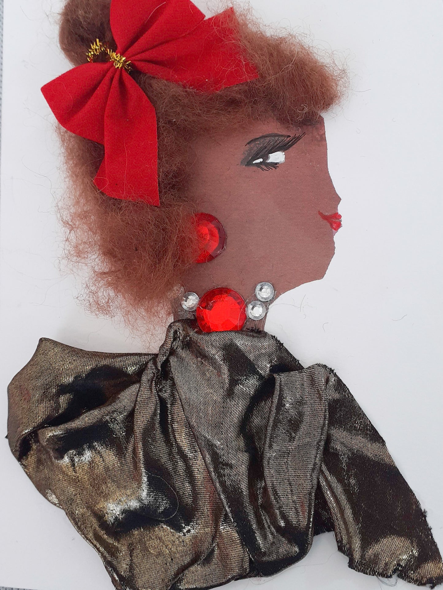 This card has been given the name Vogue. She wears a bronze fabric blouse and a necklace made up of one large red gem and several small crystal gems. She wears a large red bow in her reddish-brown hair.
