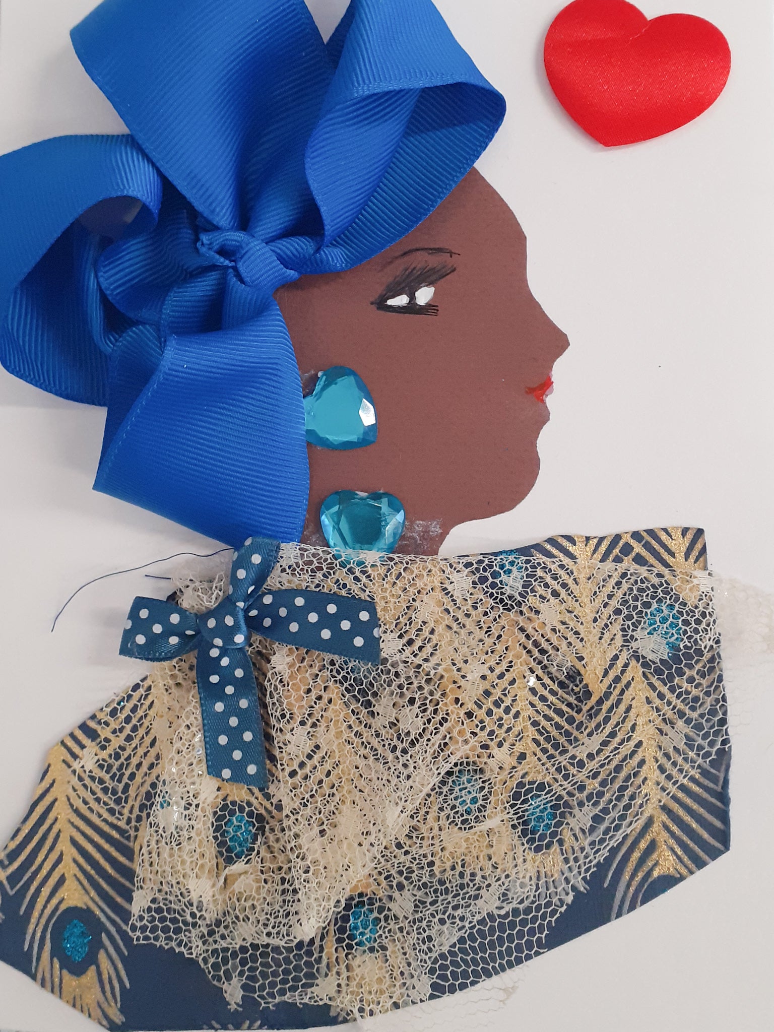 This card is given the name Colindale. Colindale wears a blue fabric which has gold peacock feather prints on it. She wears a large blue bow on her head, and has blue heart earrings and a matching necklace. There is a red heart in the top right corner of the card.
