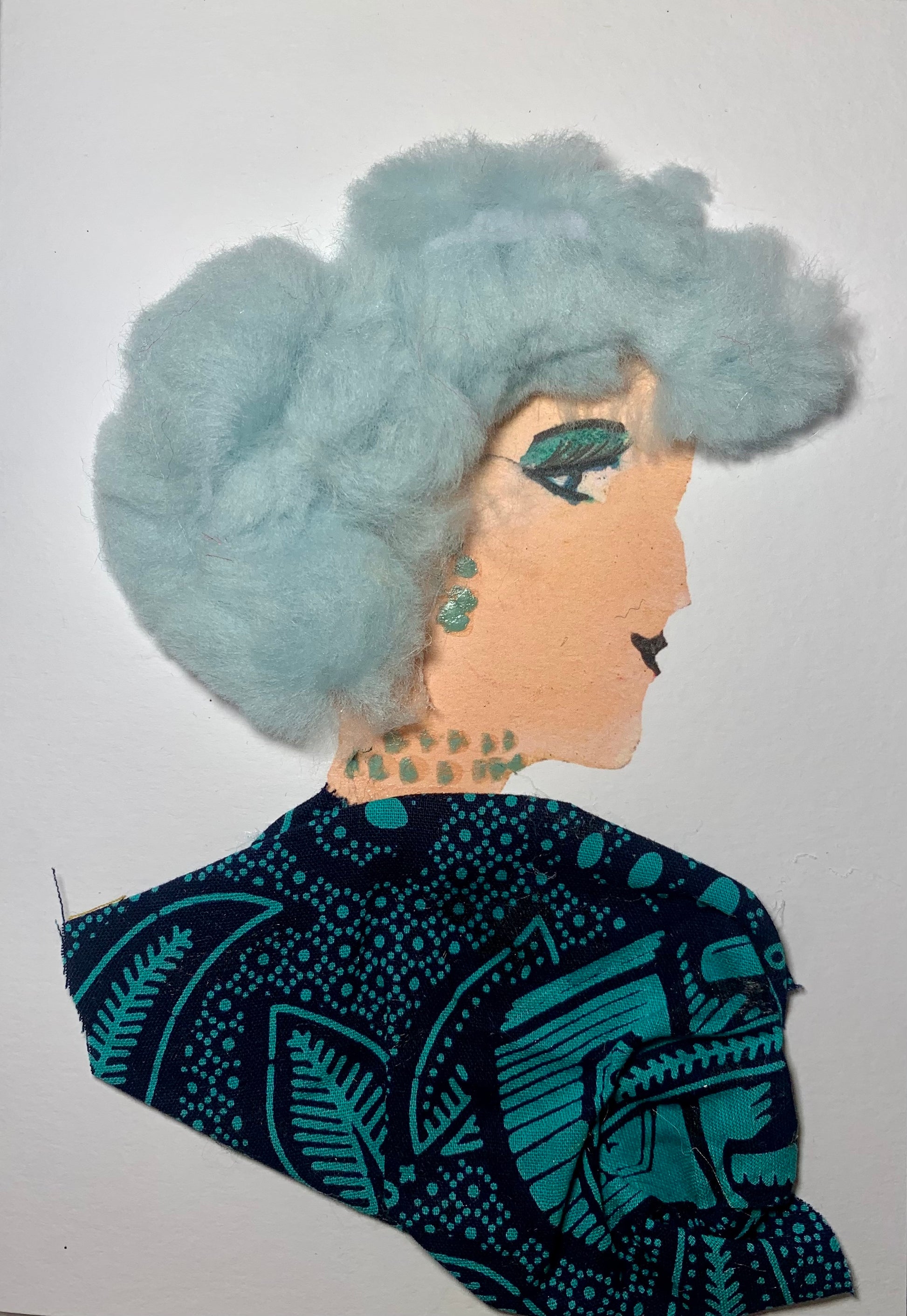 This card is of a woman given the name Freda. Freda wears a nature patterned blouse that is turquoise and black. Her jewellery is dainty and blue. He hair is blue and almost cotton like.