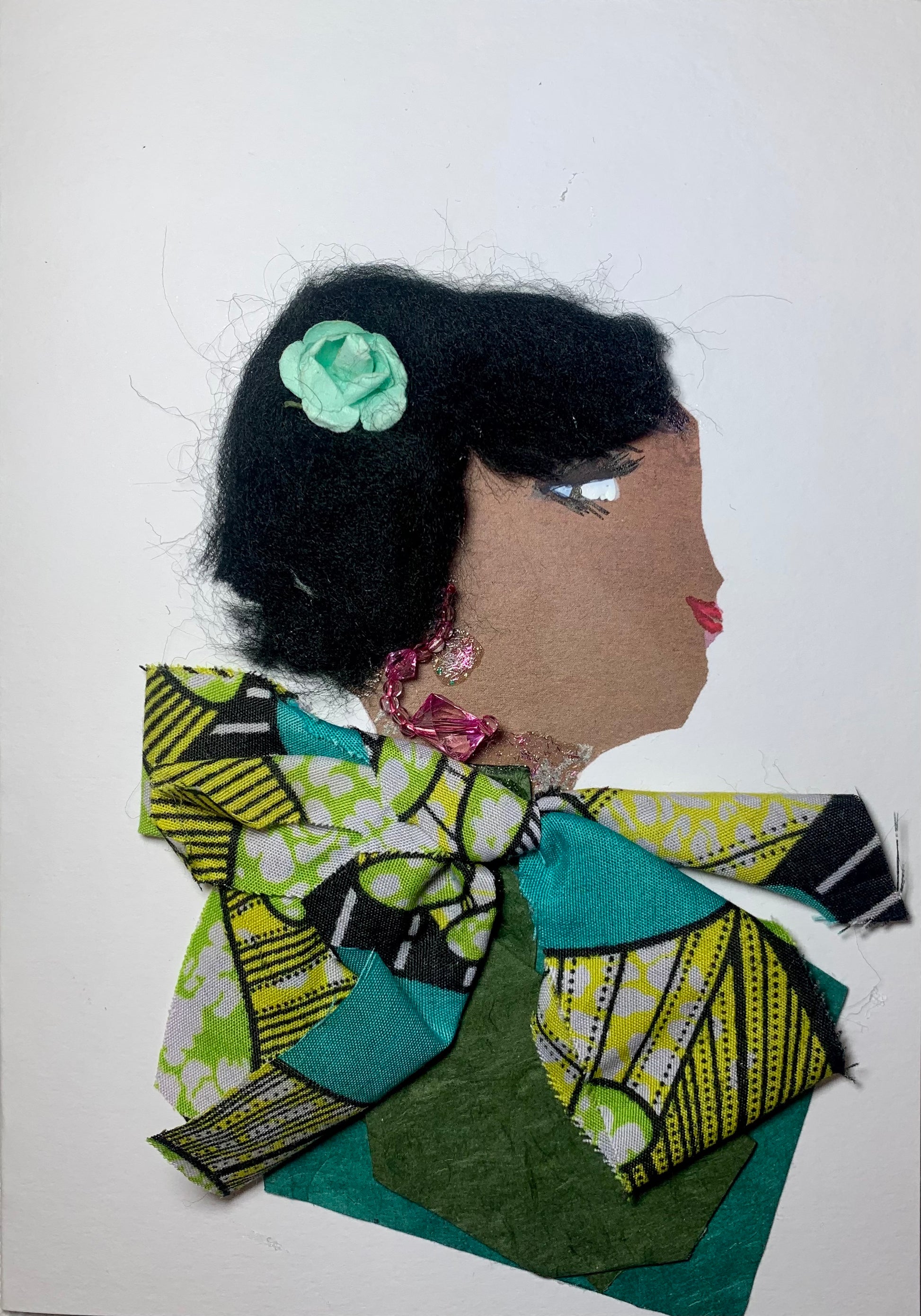 This card has been given the name Great Green. Great green wears a green, turquoise, and yellow printed blouse and has a light blue flower in her short black hair. Her earring is pink crystal and beaded.