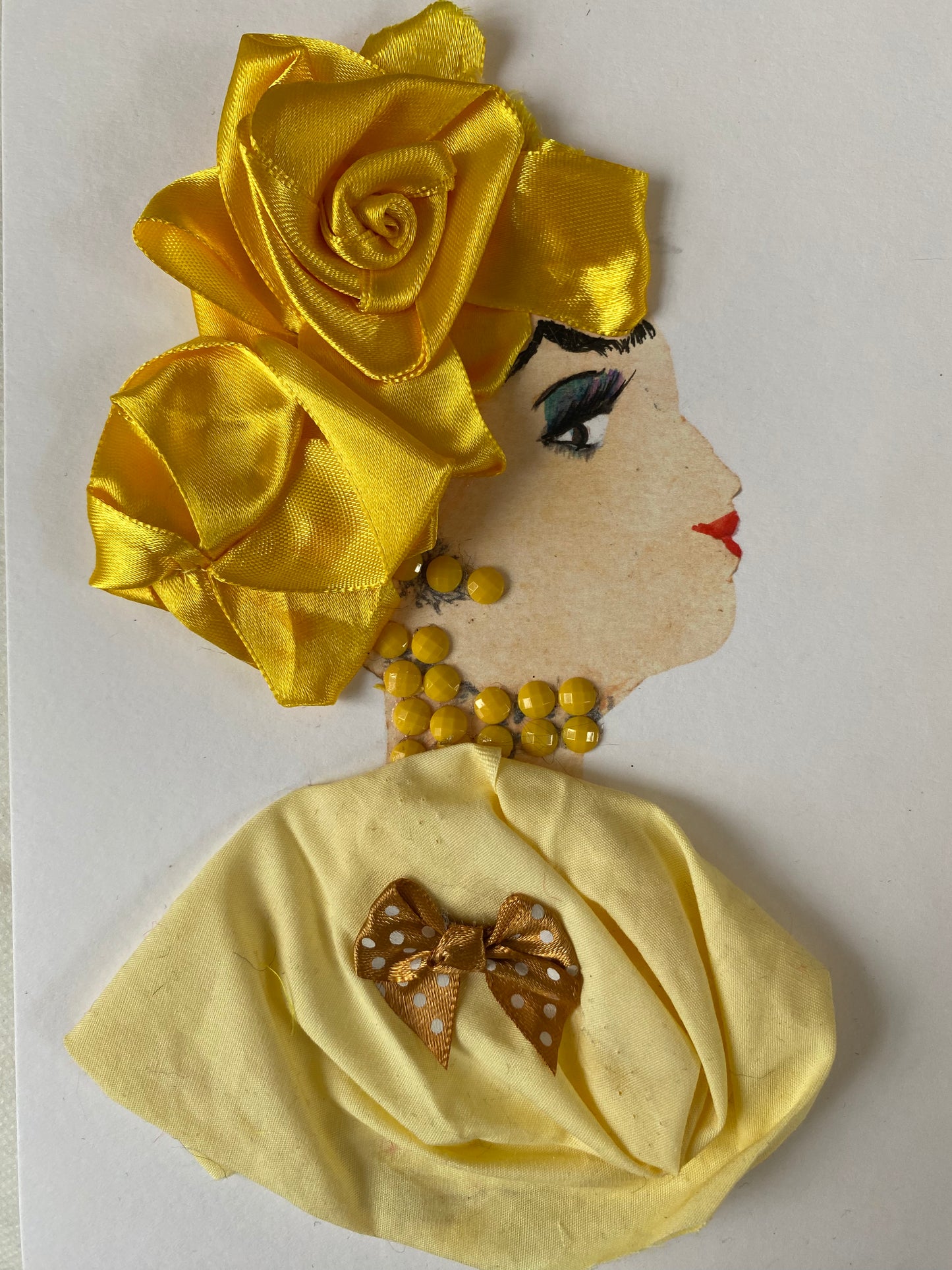 I designed this card of a woman named Lucy Lovely. She has a white skin tone who wears a beautiful golden rose head wrap. She wears a delicate yellow blouse with a polka dot bow on the front. She wears dazzling yellow jewellery.