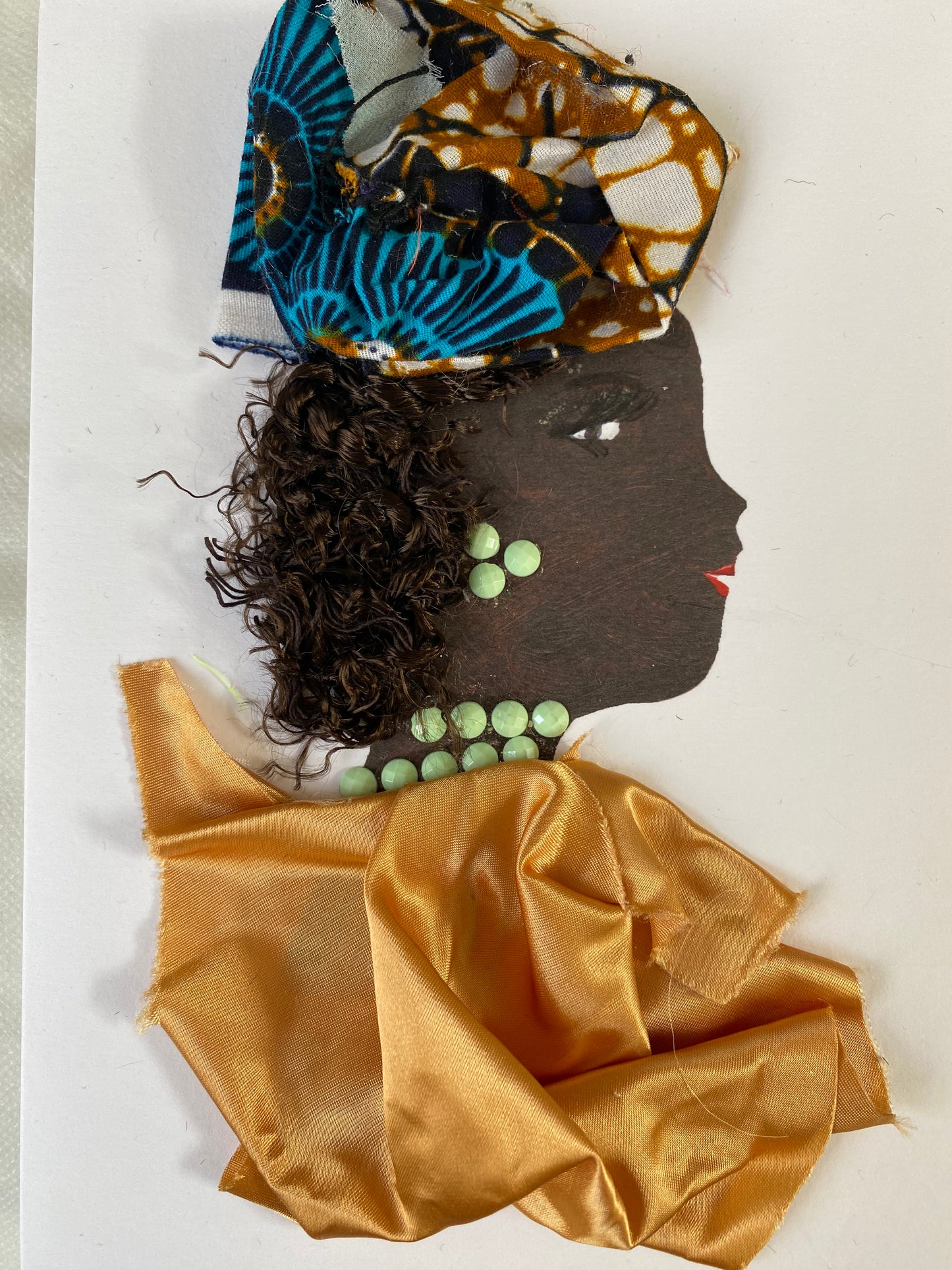 I designed this card of a woman named Naomi Novlita. She has a black skin tone and is wearing a divine ankara hatinator. She wears a silky gold blouse. She wears dazzling bright green jewellery.