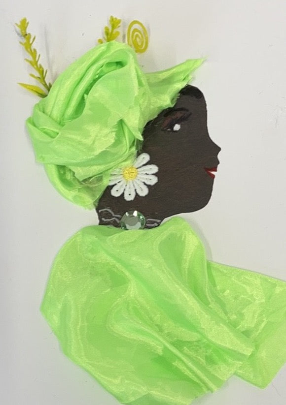 This card is of a woman given the name Green Tomato. Green wears a matching green headscarf and blouse which are both a silky material. Her earring is a white daisy, and her necklace as a single diamanté gem.
