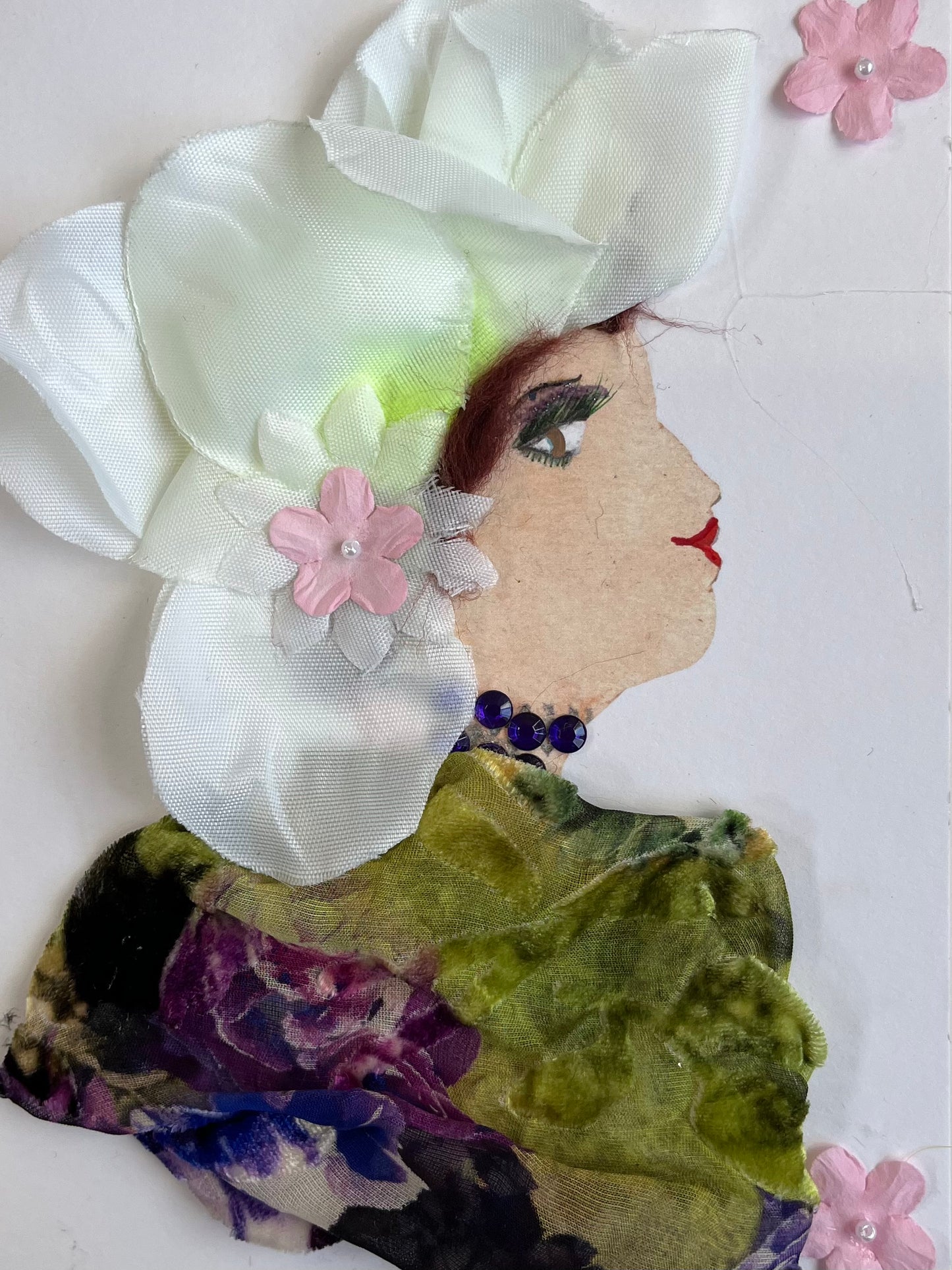This card is called Regan. She wears a floral print blouse and white petals in her hair.