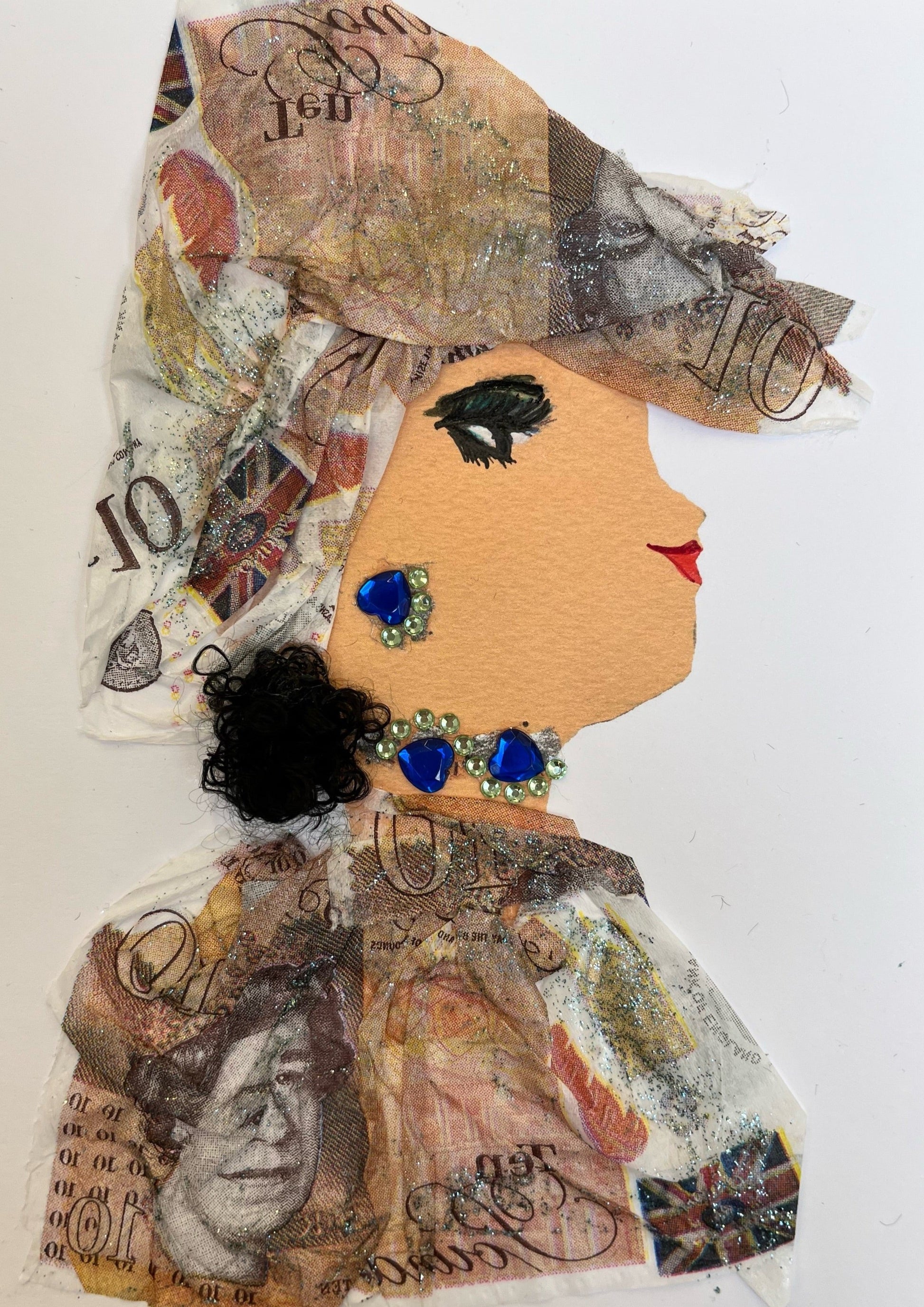 This card is called Amoni. She wears a money printed fabric as her blouse and headscarf. Her short blakc ponytail can be seen out of the bottom. She wears blue and green gem jewellery.