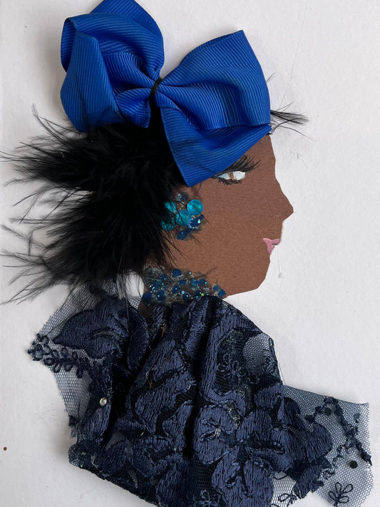 This card is of a woman given the name Bella. Bella wears a dark navy blue lace blouse and lighter blue gem jewellery. Her hair is black and feathery, and has a large blue bow in it. 
