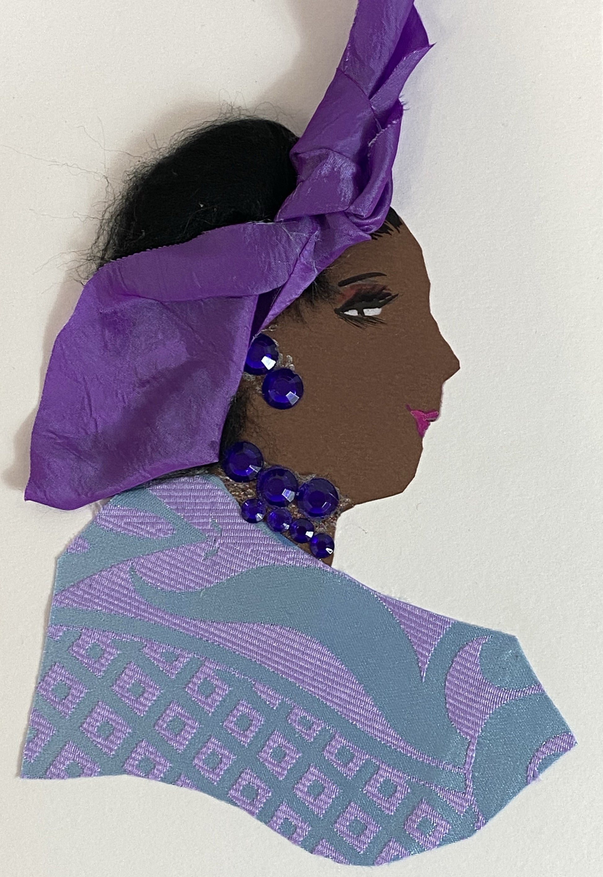 This card is called Peju. She wears a patterned blouse which is light blue and lavender, and a purple headscarf in her black hair.
