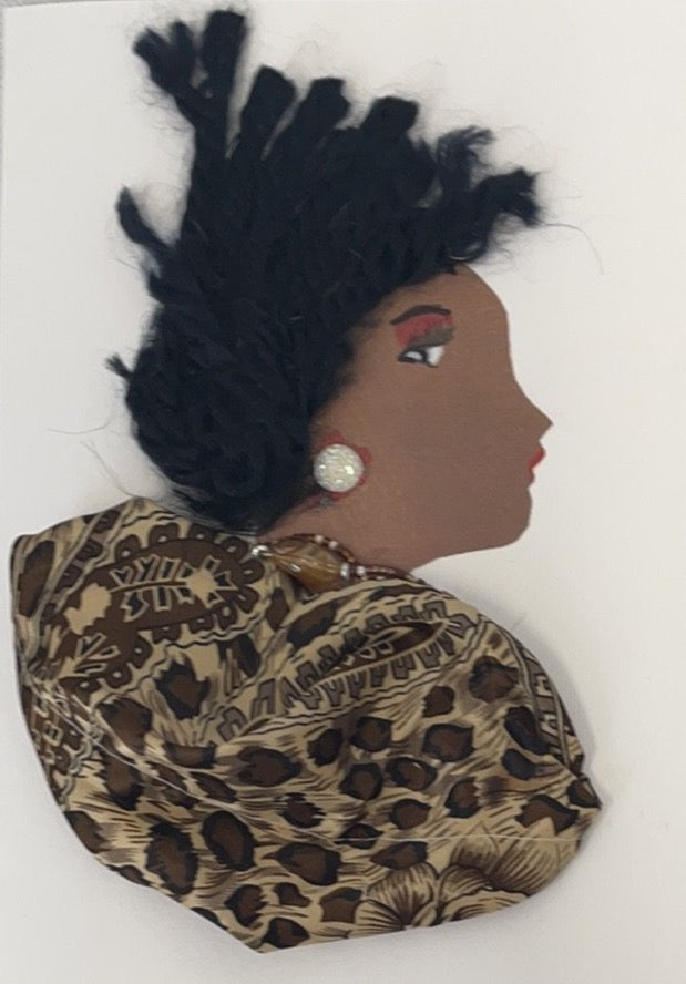 This card is called Tola, and she is wearing a brown animal print blouse. She has black curly hair which she wears in an updo.