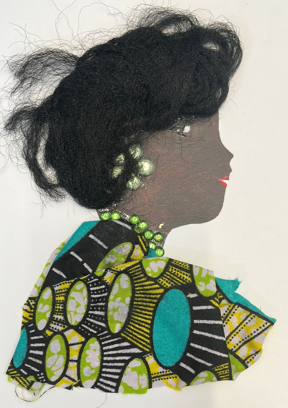 This card is of a woman named Danika, who is wearing a distinctly patterned green, turquoise, yellow, black and white blouse. Her necklace is made of green gems, and her earring is a green flower. Her hair is short and black.