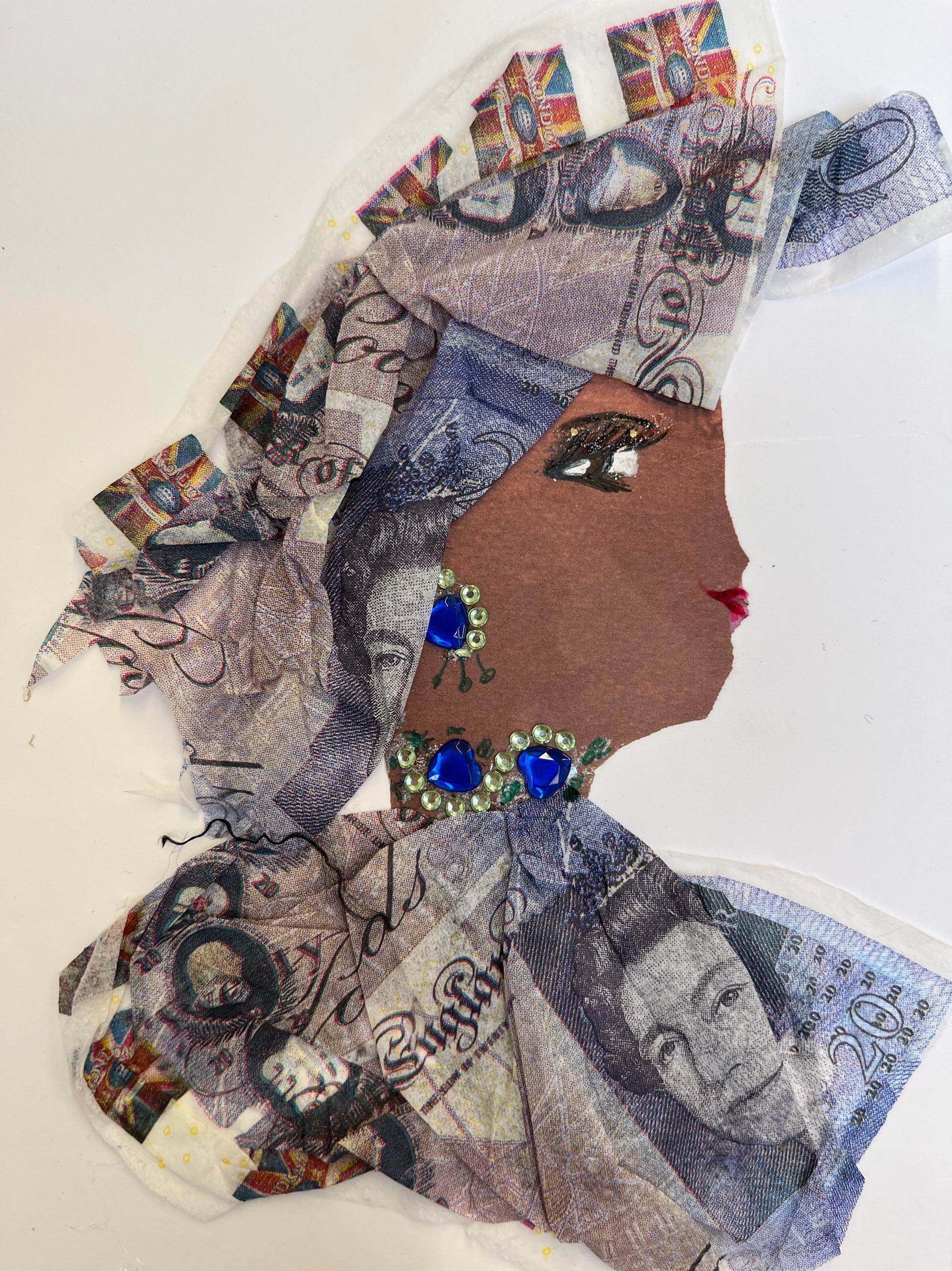 This card has been given the name avery, and she wears a matching headdress and blouse made of a money fabric. She wears blue and green gem jewellery.
