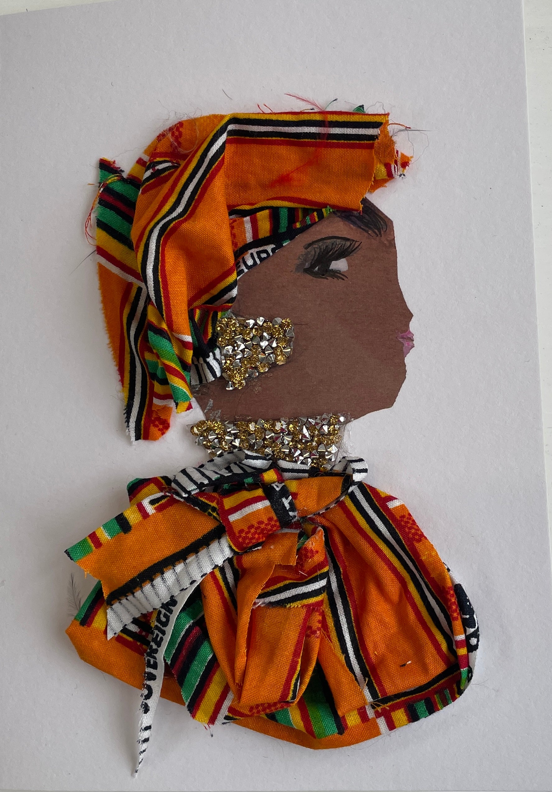 This card is called Goldie. She wears an orange patterned headdress and blouse, and gold diamanté jewellery.