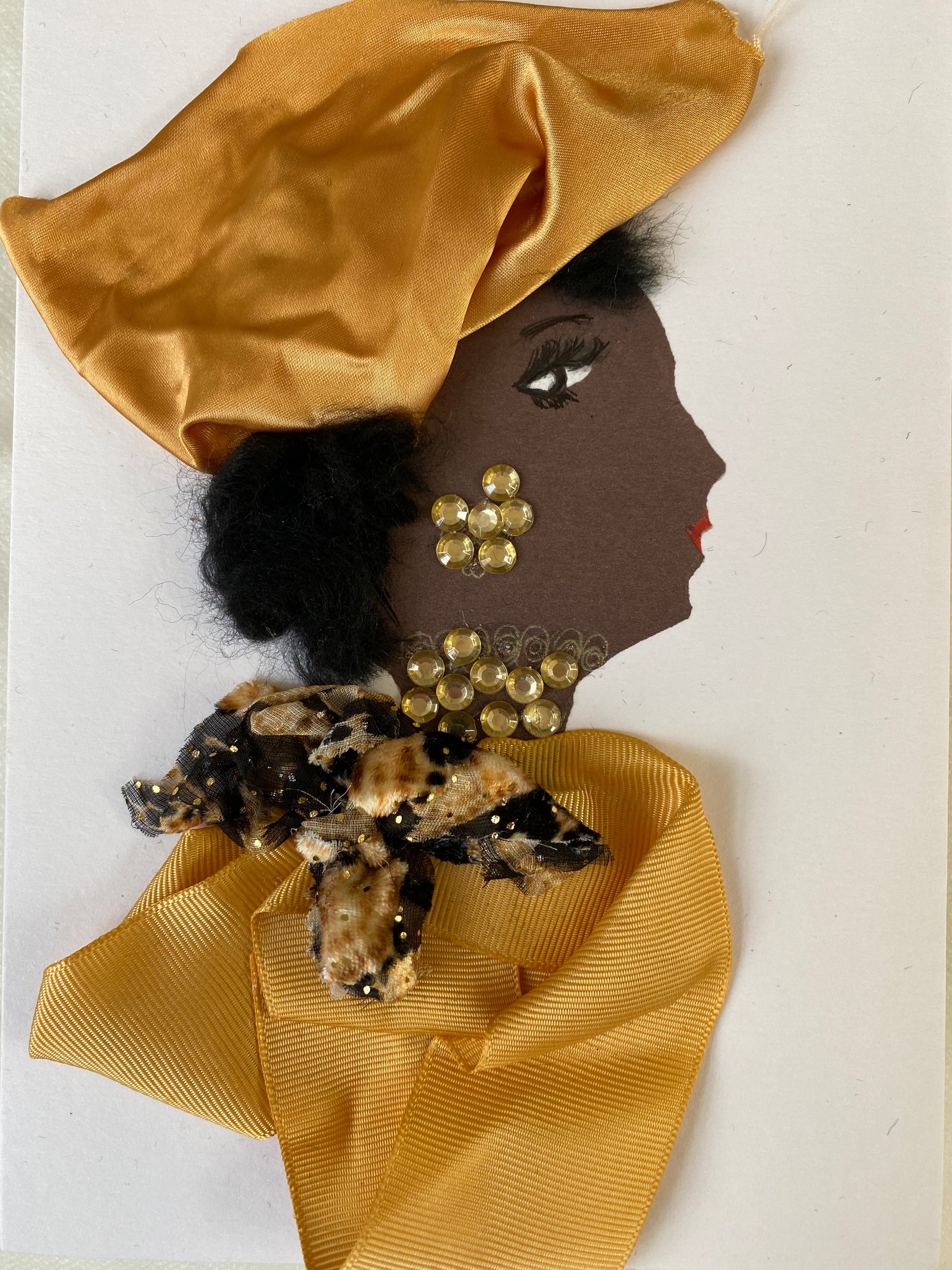I designed this card of a woman named Doctor Goldhawk. She has a black skin tone and is wearing a luscious silk gold hat. She wears a beautiful bow around her neck with a silky gold blouse. She wears dazzling gold jewellery.