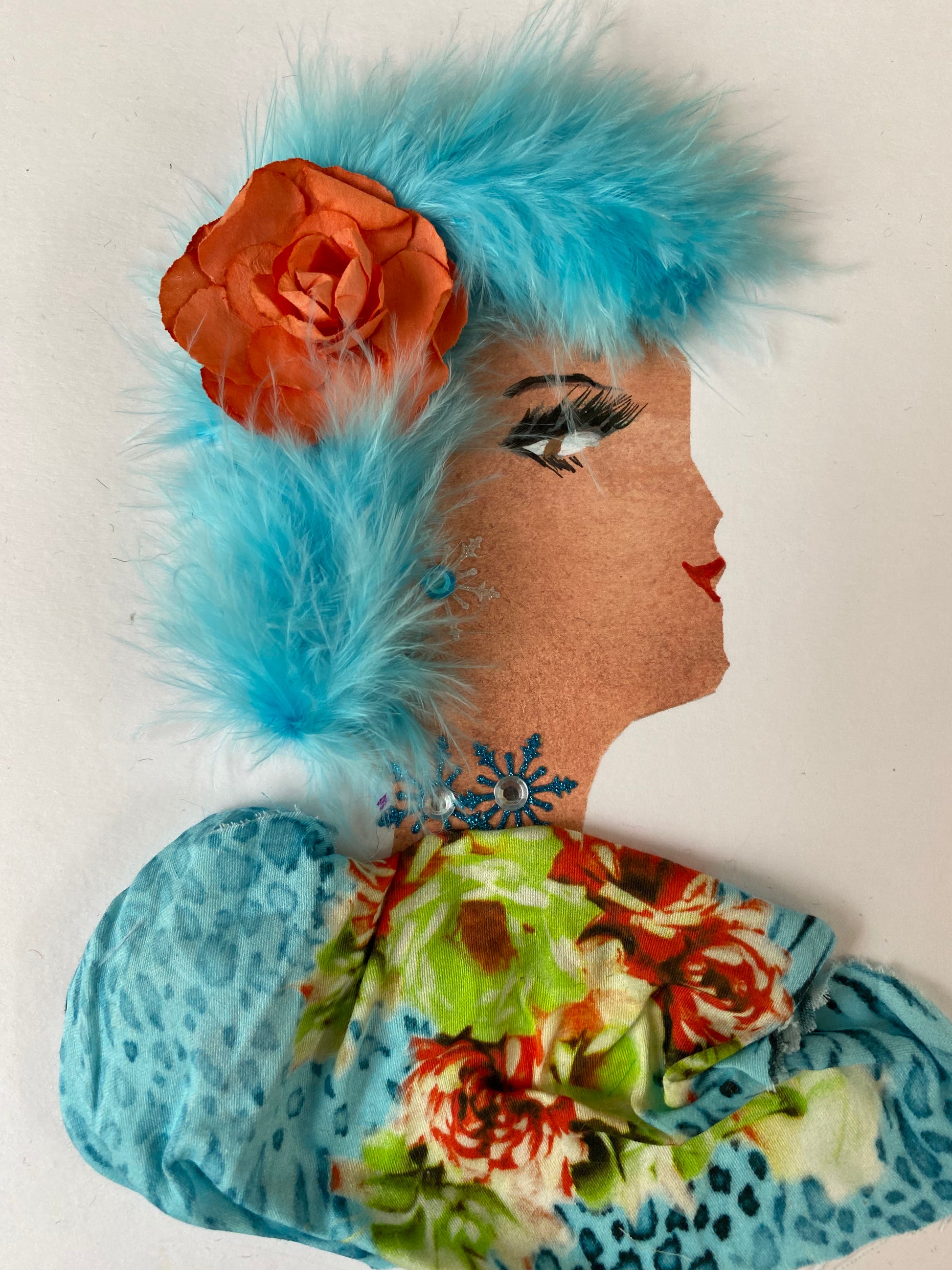 I designed this handmade card of a woman named Blueberry Cherry. She has a white skin tone and is wearing a beautiful orange flower in her hair. She wears a gorgeous blue, orange, and green patterned blouse. She wears sparkly blue jewellery.
