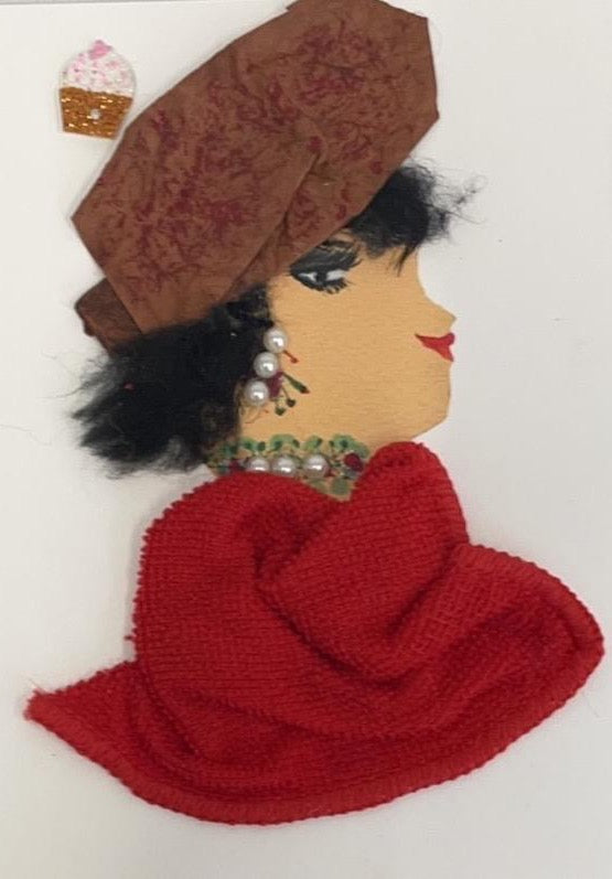 This card has been called Red Ruislip Ruby. She wears a red towel material blouse and a brown hat. In the top left corner, she has a cupcake sticker.