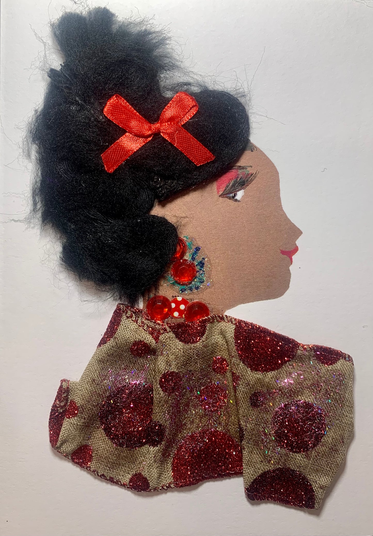 This card is of a woman named Vero Paris. She wears a blouse with red glitter polka dots on it. Her jewellery is made of red gems, and there is a red bow in her black hair.