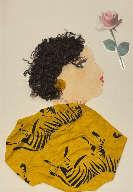Handmade greeting card that can double as a piece of art featuring a side-profile portrait of a woman with short, curly dark hair made from textured material, a soft pink rose placed behind her head, and a mustard-yellow patterned garment with black leaf designs. The face is softly painted with delicate lashes and red lips, and the overall composition combines fabric and paper elements to create a warm, elegant, and textured mixed-media design.