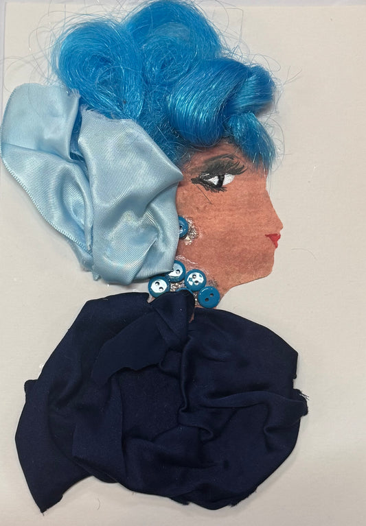 Handmade greeting card that doubles as a piece of art featuring a woman with vivid blue sculpted hair styled into soft, flowing curls that give a dimensional, textured appearance. A satin bow is placed within the hair, adding a smooth, glossy contrast to the structured curls. She wears a dark fabric garment that provides a strong base tone for the composition, allowing the blue elements to stand out more prominently. Small blue button details act as a matching jewllery set for a necklace and earrings. 