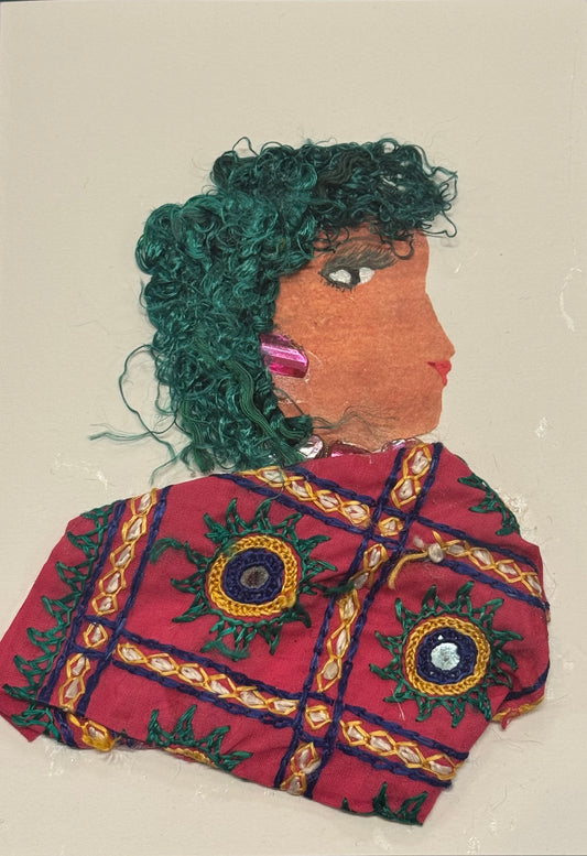 
Handmade greeting card that can double as art, side-profile collage portrait of a woman facing right, with textured green curly yarn hair. Her skin is a warm tan tone, and she wears a deep red garment decorated with intricate embroidered patterns in gold, green, and blue circular designs. A pink, faceted earring adds a pop of shine. Her expression is calm and composed, with a softly defined eye and red lips. The materials appear layered and tactile, with visible stitching and fabric textures creating depth