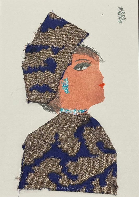 Handmade greeting card that doubles as a piece of art featuring a side-profile collage of a woman wearing a beige and blue patterned headscarf that wraps smoothly around her head. The matching garment forms a blouse with the same repeating pattern, creating a cohesive and balanced look. Blue embellishments decorate her cheek and extend toward the neck area, adding small pops of color and subtle sparkle against the neutral tones. The materials appear fabric-focused, with visible texture and layered pieces. 