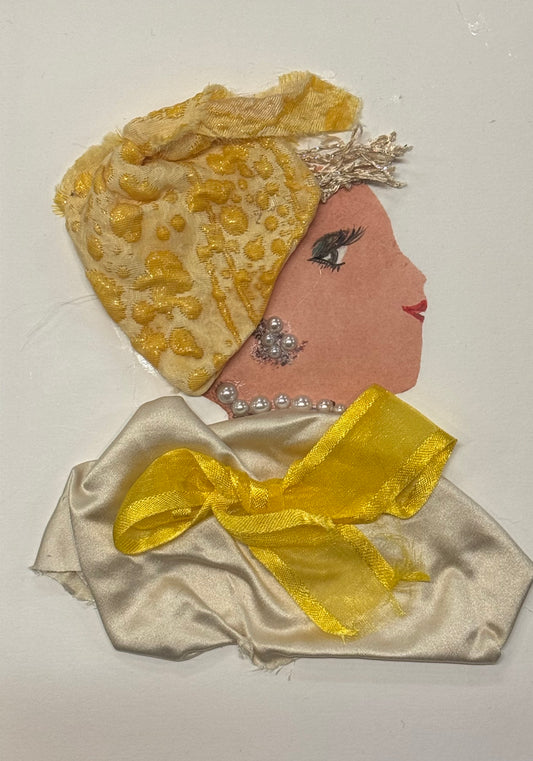 Handmade greeting card that can double as a piece of art, featuring a side-profile silhouette of a woman with a warm-toned complexion wearing a gold-patterned headwrap, pearl earrings and necklace, and a silky cream outfit accented with a sheer yellow bow, arranged on a white background.