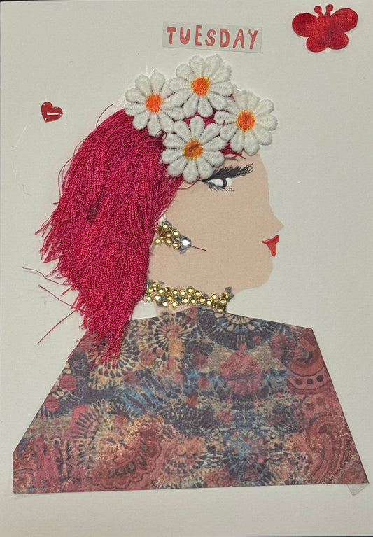 Handmade greeting card that can double as a piece of art, featuring a light-skinned side-profile silhouette with bright pink textured hair, decorated with white daisy flowers, wearing gold gem earrings and necklace and a detailed patterned fabric top, with the word “Tuesday” displayed above on a white background.