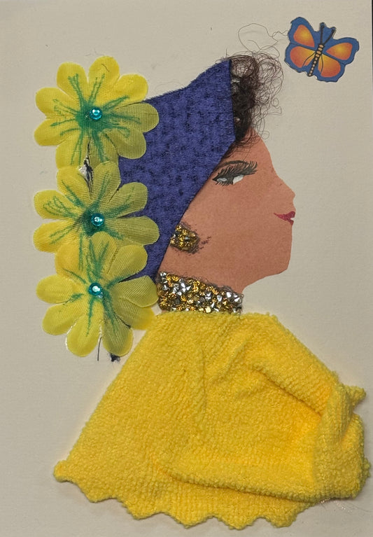 Handmade greeting card that can double as a piece of art featuring a side-profile silhouette of a woman with a warm tan complexion wearing a textured yellow sweater and a deep purple headwrap. Bright yellow flower embellishments with green details line the side of her head, accented with small blue gem centers. She wears gold glitter earrings and a matching necklace. A small colorful butterfly appears near her head, and her facial features include detailed lashes and red lips, all on a white background.