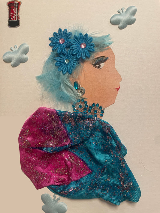 This is a handmade card of a woman named Beacontree Betty. She has pastel blue fuzzy hair with teal flowers, wears sparkly blue jewellery and a bright blue-and-pink dress. Stickers include a red telephone box and multiple butterflies.