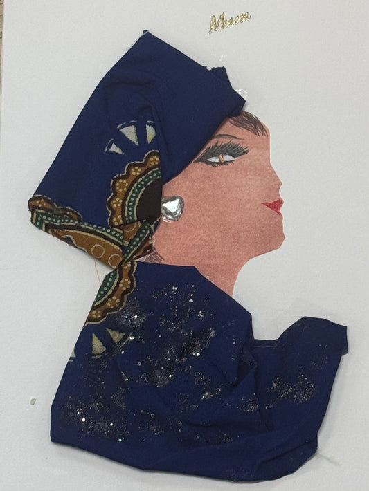 Handmade greeting card that can double as a piece of art, depicting a woman in profile wearing a navy and patterned headscarf with gold and green details. She is dressed in a deep blue fabric garment with subtle glitter accents and a silver-toned earring. Above her head there is a small detailed gold sticker that reads "Mum". 