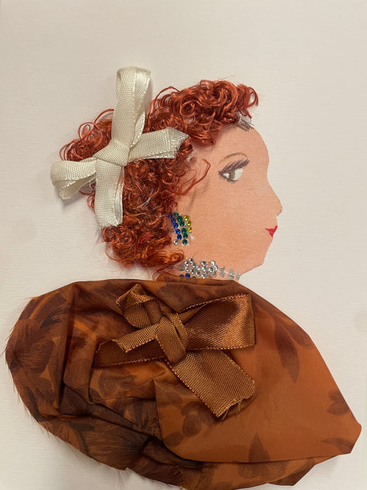 Handmade greeting card featuring a side-profile of a woman with curly red hair adorned with a cream ribbon bow. She wears colorful beaded earrings, a sparkly silver necklace, and a rich chestnut brown fabric top with a large satin bow. The card has a textured, dimensional design with a white background.