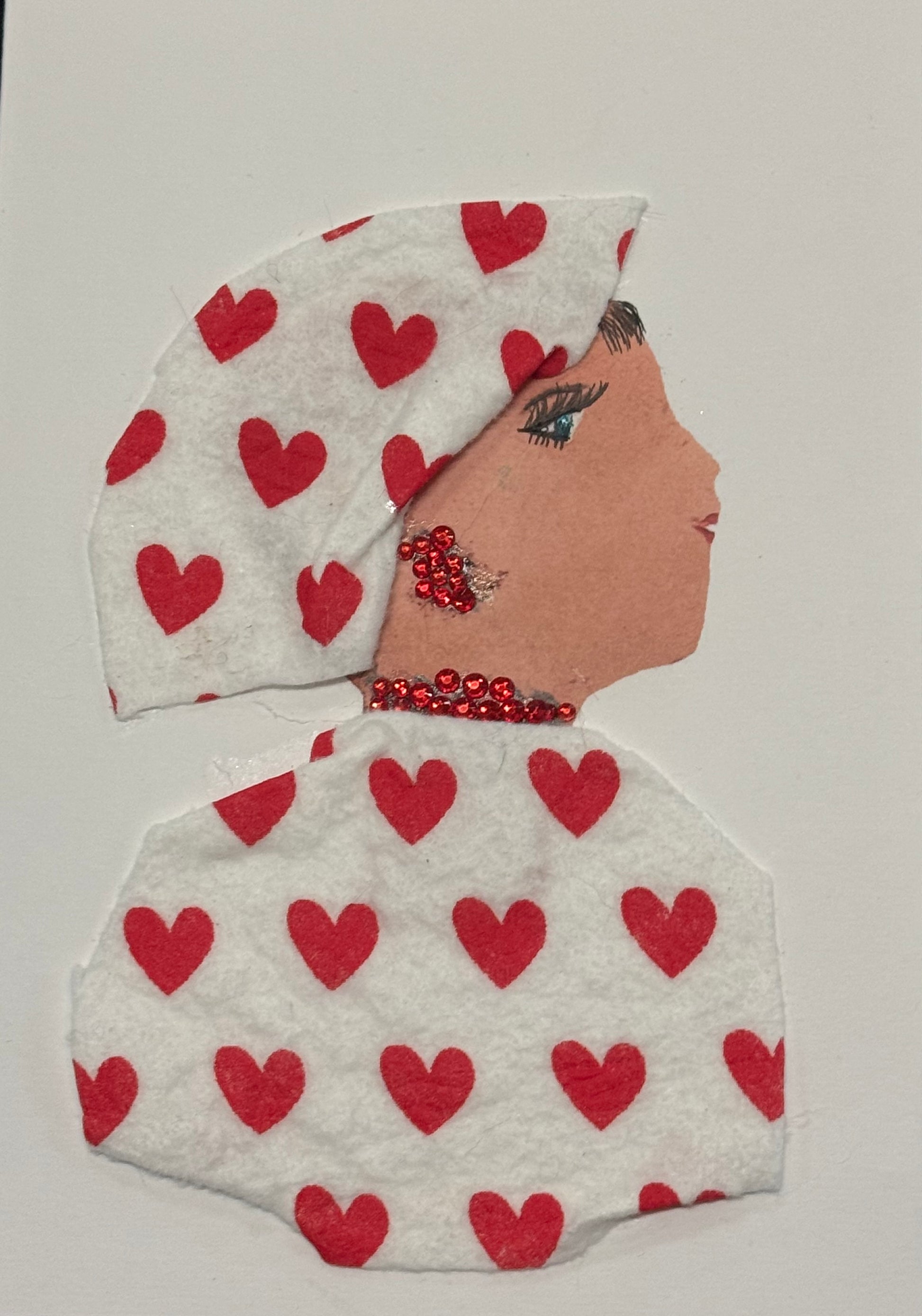 Handmade greeting card that doubles as a piece of art featuring a side-profile collage of a woman set against a clean white background. She wears a white headscarf and matching white outfit, both carefully decorated with evenly spaced small red heart patterns that create a soft, romantic rhythm across the design. Her jewelry includes bright red rhinestone earrings and a matching necklace that catch the light and add dimension to the otherwise minimal palette. 