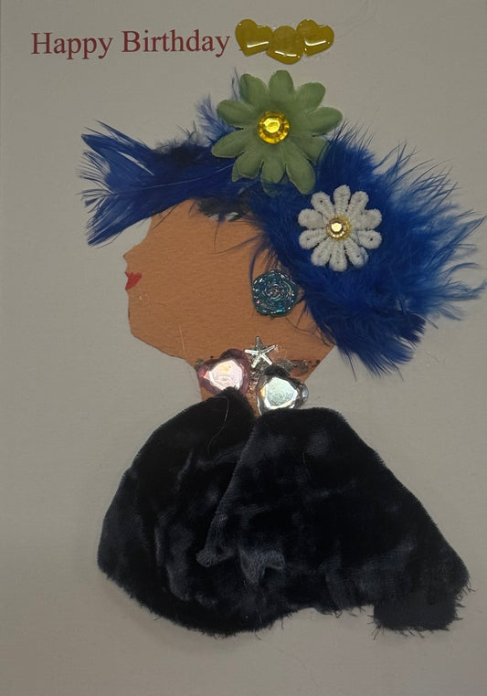 Handmade birthday card that can double as a piece of art featuring a woman with spiky blue hair that is textured by blue feathers and has two decorative flower gems in her hair. She is dressed in black velvet with sparkling jewelry that consits of blue rose shapped earrings and a silver star and heart necklace, creating a glamorous party look.