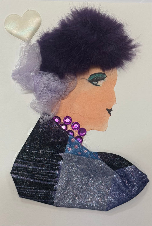Handmade greeting card that can double as a piece of art, featuring a side-profile illustration of a woman with deep purple faux-fur hair styled in a voluminous shape, accented with soft lilac netting. She wears a layered dark-toned garment with shimmering silver and navy fabrics, along with a bold purple gem necklace, set against a neutral background with a satin heart embellishment. Also detailed in the top left corner is a puffy white heart embelishment above her head. 