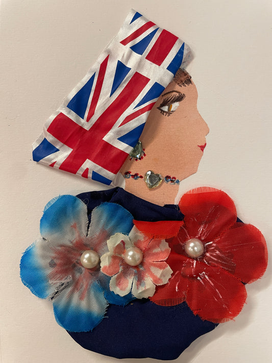 This is a handmade card of a woman named Elena Union. She wears a UK Flag printed wrap, a navy outfit with large red, white, and blue fabric flowers, and pearl accents.