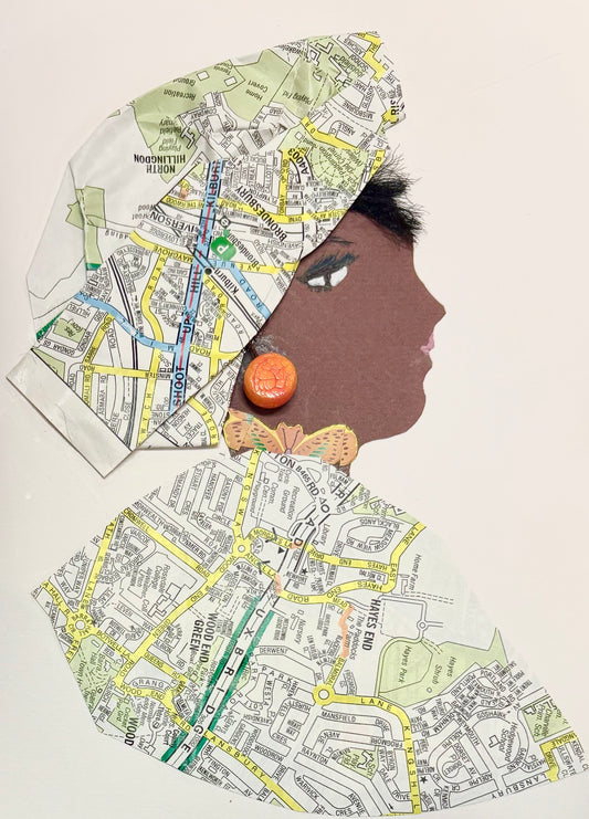 A woman wears a headwrap and blouse featuring a map pattern with green, white, and yellow. She wears a bright orange earring in a circle shape and a butterfly necklace peaking through the neckline of her blouse. 